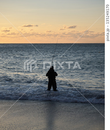 夕暮れの海に立つ釣り人のシルエット 135249170