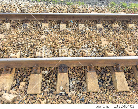 Close-up of railway tracks with gravel stones and wooden sleepers Close-up of railway tracks with gravel stones and wooden sleepers 135249403