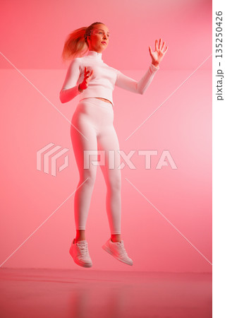 Woman in smartglasses jumping against red background Woman in smartglasses jumping against red background 135250426