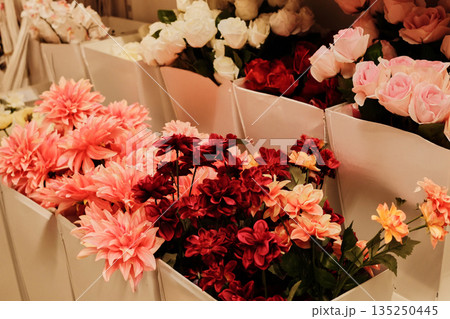 Decorative display of pink and red artificial flowers arranged in white containers. The concept represents romance, creativity, and elegant home decoration Decorative display of pink and red artificial flowers arranged in white containers. The concept represents romance, creativity, and elegant home decoration 135250445