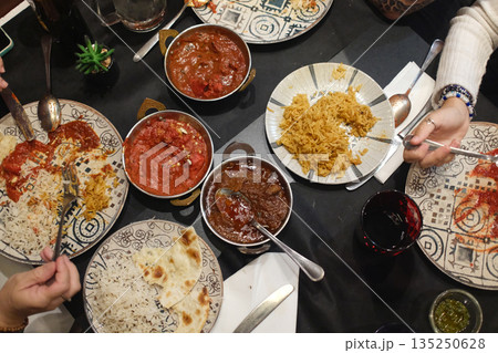 Traditional Indian meals with colorful spices, rice, curry and flatbread served on decorated table. Traditional Indian meals with colorful spices, rice, curry and flatbread served on decorated table. 135250628
