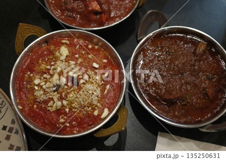 Traditional Indian meals with colorful spices, rice, curry and flatbread served on decorated table. Traditional Indian meals with colorful spices, rice, curry and flatbread served on decorated table. 135250631