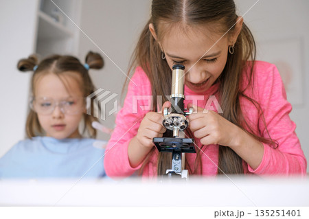 A child takes a close-up look at microorganisms made of biological material under a microscope. School cognitive biology and chemistry lessons 135251401