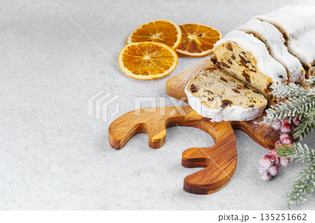 Traditional sliced Christmas stollen loaf with raisins and powdered sugar on wooden cutting board 135251662
