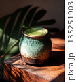 Matcha drink in a handcrafted ceramic cup with natural light and green plant backdrop 135251903