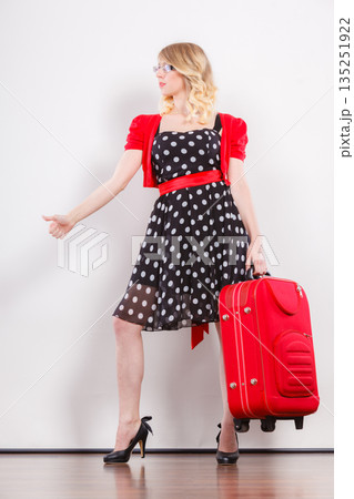 woman with red suitcase hitchhiking 135251922