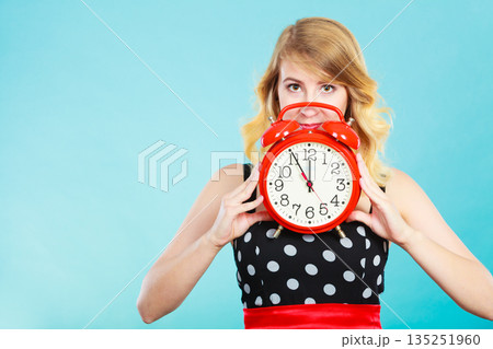 Serious girl with alarm clock on blue. Serious girl with alarm clock on blue. 135251960