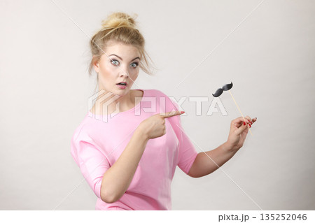 Happy woman holding fake moustache on stick 135252046