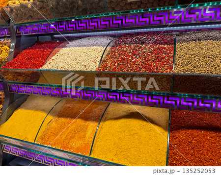 Colorful ground spices arranged in glass bins in Istanbul bazaar. Culinary diversity, visual order, sensory richness, and cultural identity expressed through traditional spice market layout. Colorful ground spices arranged in glass bins in Istanbul bazaar. Culinary diversity, visual order, sensory richness, and cultural identity expressed through traditional spice market layout. 135252053