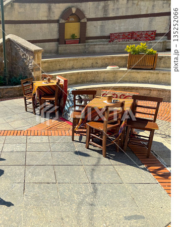 Outdoor cafe tables with patterned fabrics and wooden chairs. Hospitality, relaxation, and social lifestyle in a historic courtyard. Outdoor cafe tables with patterned fabrics and wooden chairs. Hospitality, relaxation, and social lifestyle in a historic courtyard. 135252066