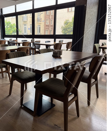 Wooden tables and chairs in a bright cafe interior. Socialization, leisure and human connection in everyday hospitality spaces. 135252067