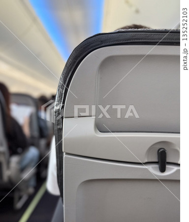Aircraft cabin interior with passenger seat back and safety instructions. Aviation, travel, and passenger service equipment for flight safety and onboard comfort system. 135252103