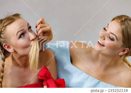 Two females playing with hair Two females playing with hair 135252119