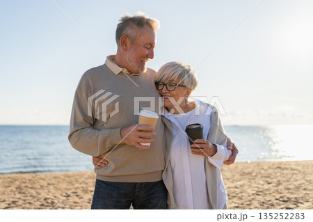 Good morning. Senior mature couple enjoying walking with paper cups of coffee. Old husband wife drinking coffee to go outdoor. Grandmother grandfather together enjoying walk. Family moment of love 135252283