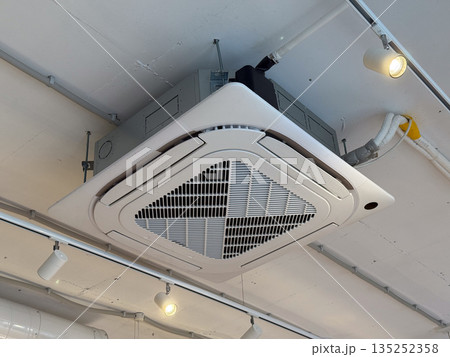 Ceiling mounted air conditioning unit in a modern commercial interior. Climate control, ventilation, and energy efficient building system Ceiling mounted air conditioning unit in a modern commercial interior. Climate control, ventilation, and energy efficient building system 135252358