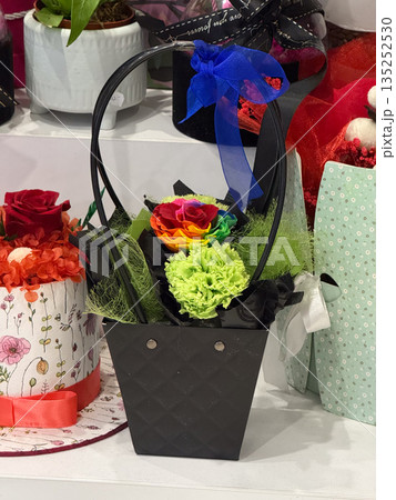 Black gift basket with rainbow rose and green carnation. Love, diversity, celebration, and joyful emotion through colorful floral arrangement 135252530