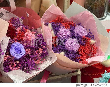 Colorful preserved rose bouquets with purple and pink flowers. Floral arrangement, romantic decor, and luxury gift shop display 135252543