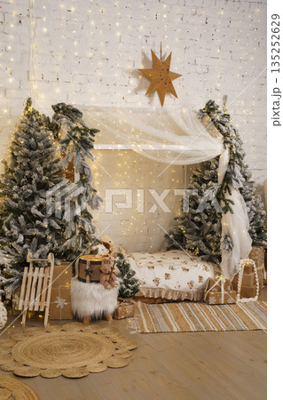 Winter holiday home decor with snowy Christmas trees, bed and warm fairy lights 135252629
