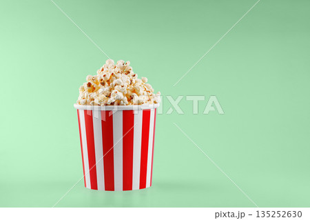 Classic red striped popcorn cardboard cup on Green background Classic red striped popcorn cardboard cup on Green background 135252630
