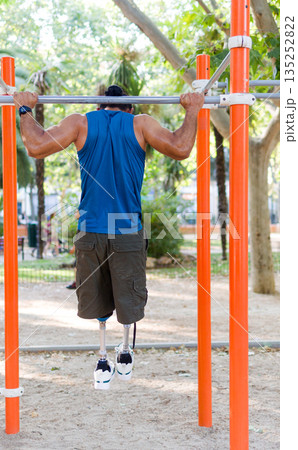 Unrecognizable Disabled athlete training pull ups in calisthenics park Unrecognizable Disabled athlete training pull ups in calisthenics park 135252822