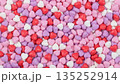 Background of colorful heart shaped candies. Top view of sweet sugar treats in pink red and purple colors. Valentine's Day texture or pattern 135252914