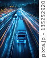Trucks driving on a highway at night with motion blur light trails. Vertical view of futuristic logistics, transportation, and supply chain technology with a city skyline 135252920