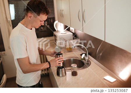 A man assembles a moka pot on the kitchen counter. The scene represents a simple morning routine concept A man assembles a moka pot on the kitchen counter. The scene represents a simple morning routine concept 135253087