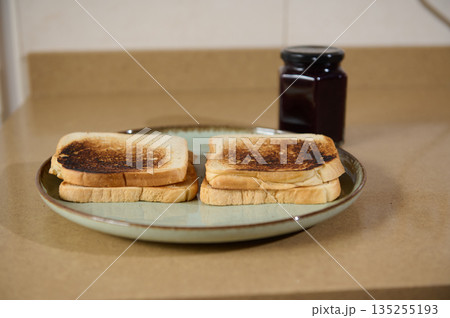 Two Toast Slices On Plate With Jam Jar In Background For Everyday Breakfast Two Toast Slices On Plate With Jam Jar In Background For Everyday Breakfast 135255193