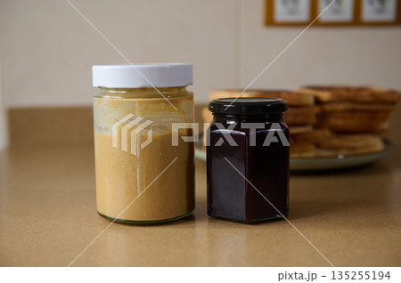 Peanut Butter And Jam Jars On Kitchen Counter With Pancake Stack In Background Peanut Butter And Jam Jars On Kitchen Counter With Pancake Stack In Background 135255194