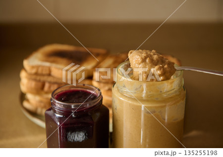 Cozy Breakfast Scene With Toast, Peanut Butter, And Jam In Glass Jars On a Plate Cozy Breakfast Scene With Toast, Peanut Butter, And Jam In Glass Jars On a Plate 135255198