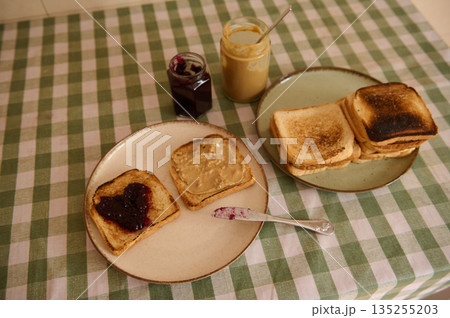 Homemade Toast Breakfast With Peanut Butter, Jam, And Toasted Bread On Green Check Tablecloth Homemade Toast Breakfast With Peanut Butter, Jam, And Toasted Bread On Green Check Tablecloth 135255203