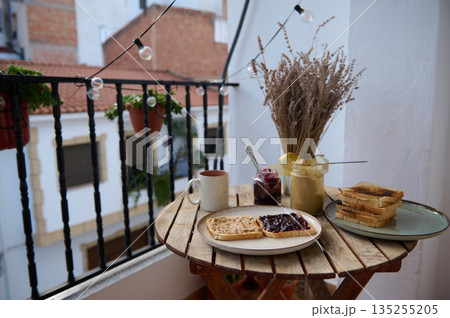 Cozy Balcony Breakfast With Toasts, Jam, And Tea On A Wooden Table With Dried Flowers 135255205