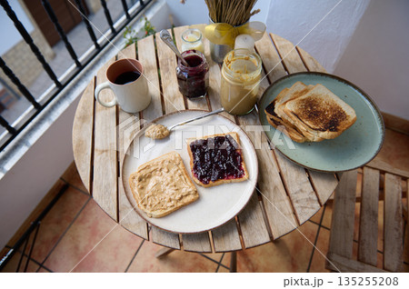 Cozy Balcony Breakfast With Toasts, Jam, Peanut Butter, Coffee, and Fresh Spreads 135255208