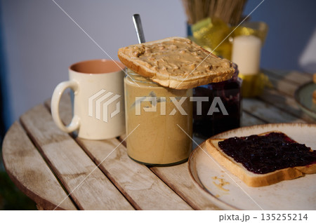 Toast With Peanut Butter On Jam Jar Morning Breakfast Scene On Wooden Table 135255214