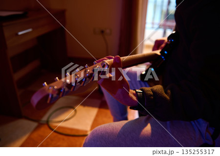Casual Musician Playing Electric Guitar In Warm Indoor Room, Focused On The Neck 135255317