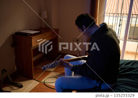Man Playing Electric Guitar In Cozy Hotel Room By Balcony Window 135255329