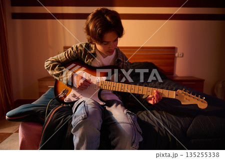 Young Guitarist Plays Electric Guitar In Cozy Bedroom, Practicing Passion And Music Skill Young Guitarist Plays Electric Guitar In Cozy Bedroom, Practicing Passion And Music Skill 135255338