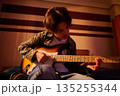 Young Guitarist Playing Electric Guitar At Home In Warm Moody Lighting 135255344