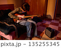 Young Musician Playing Electric Guitar in Cozy Bedroom With Amplifier on Checkered Floor 135255345