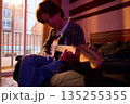 Young Man Playing Electric Guitar In Bedroom With Warm Sunset Light And Relaxed Vibe Atmosphere 135255355