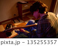 Young Man Playing Electric Guitar at Home in Warm Lighting, Focused Music Practice 135255357
