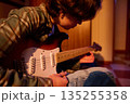 Young Musician Sits With Electric Guitar In Warm Cozy Room, Focused On Practice 135255358