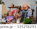 Gentle grandfather instructs young one in mixing ingredients carefully, Experienced grandfather demonstrates how to blend batter while young child observes attentively 135256293