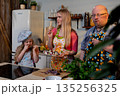 Learning cooking with family fun, Mother teaches daughter tasting while father observes nearby, Family engaged in handson cooking lesson with sauce bowls and herbs on counter 135256325