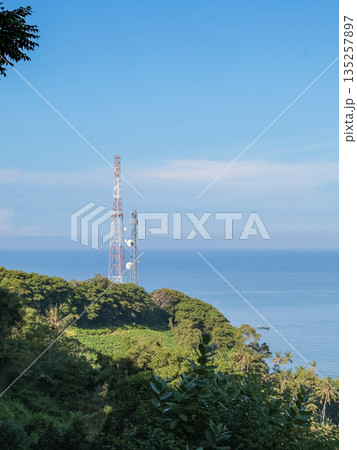Cell Tower on Lush Green Hilltop Overlooking Blue Ocean Under Bright Sky, Offering Cellular Connectivity in Coastal Regions for Modern Communication Cell Tower on Lush Green Hilltop Overlooking Blue Ocean Under Bright Sky, Offering Cellular Connectivity in Coastal Regions for Modern Communication 135257897