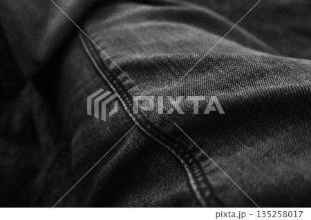 Detailed black denim texture with prominent seam and folded fabric, creating a versatile background for fashion or grunge designs Detailed black denim texture with prominent seam and folded fabric, creating a versatile background for fashion or grunge designs 135258017
