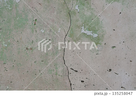Cracked Concrete Wall Surface with Green Paint Residue Showing Damage and Weathering, Suitable for Construction Defect or Renovation Concept 135258047