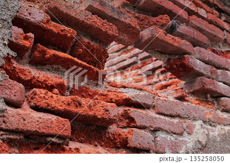 Old weathered brick wall with missing bricks showing inner structure, perfect for vintage textures and backgrounds in construction projects 135258050