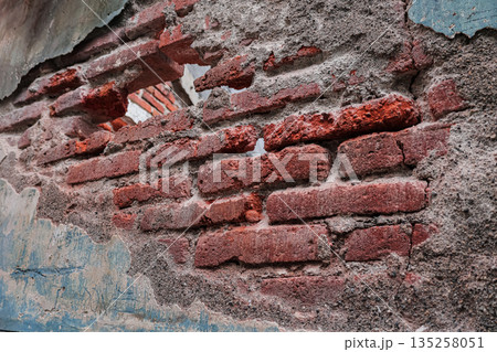 Distressed brick wall texture with crumbling plaster and weathered surface, showing age and decay for background or design element use 135258051