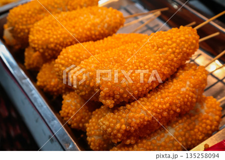 Deep-Fried Corn Dogs Displayed on Metal Rack with Textured Coating under Natural Light, Perfect for Fast Food Concepts 135258094